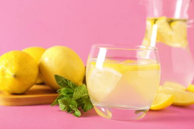 Bir bardak taze limonata ve pembe arka planda nane şekeri.