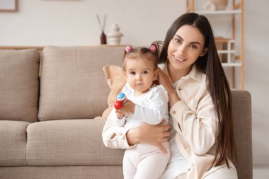 Anne ve bebeği evde marakas yiyor.