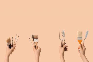 Bej arka planda sanatçı araçlarına sahip kadın eller