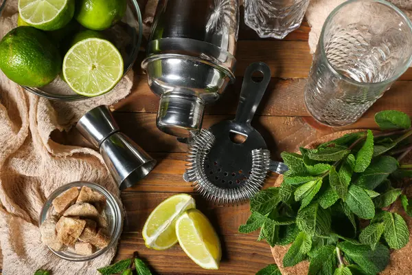 Tahta arka planda mojito hazırlamak için ölçü kabı, süzgeç ve malzemeler.
