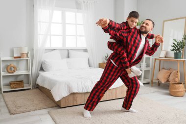 Kareli pijamalı mutlu baba oğluyla evde eğleniyor.