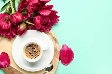 Güzel şakayık çiçekleri ve turkuaz arka planda bir fincan sıcak kahve.