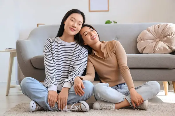 Güzel, genç, mutlu Asyalı kız kardeşler evde yerde oturuyor.