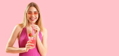 Mayo giymiş güzel, mutlu bir kadın pembe arka planda lezzetli çilekli mojito tutuyor ve mesaj için yeri var.