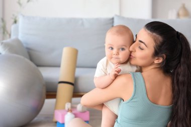 Sportif genç bir kadın bebeğini öpüyor.