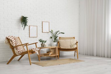 Kahve masası ve koltuklar odanın içindeki beyaz tuğla duvarın yanında.