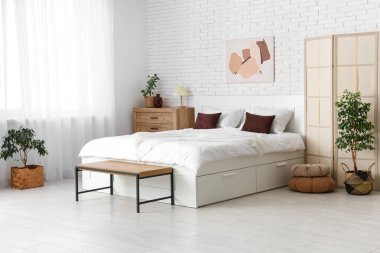 Büyük yataklı, katlanır ekran ve bitkilerle aydınlatma odasının içinde.