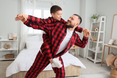 Kareli pijamalı mutlu baba oğluyla evde eğleniyor.