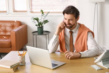 Ofiste cep telefonuyla konuşan yakışıklı bir iş adamı.