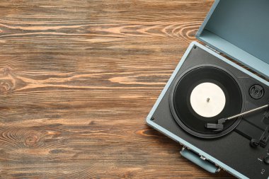 Ahşap arkaplanda vinil diski olan kayıt çalar