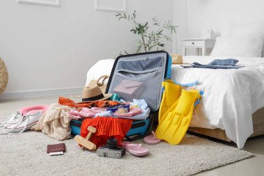 İçinde giysiler ve plaj aksesuarları olan bavulu aç.