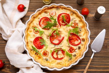 Ahşap arka planda roka yapraklı lezzetli domates tartı.