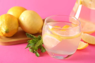 Pembe arka planda naneli ve limonlu bir bardak taze limonata.