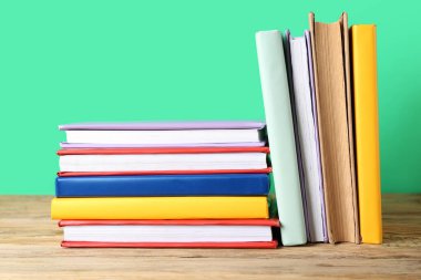 Birçok renkli kitap yeşil arka plana karşı ahşap masa üzerinde