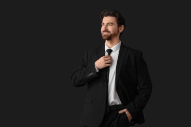 Siyah arka planda şık takım elbiseli yakışıklı iş adamı.
