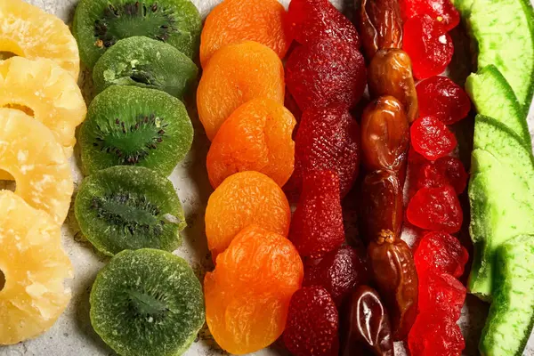 Gri arka planda farklı şekerli meyveler, yakın plan
