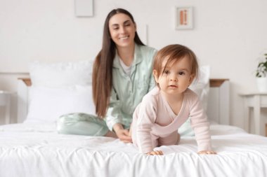 Annesiyle yatak odasında sürünen tatlı bir kız bebek.