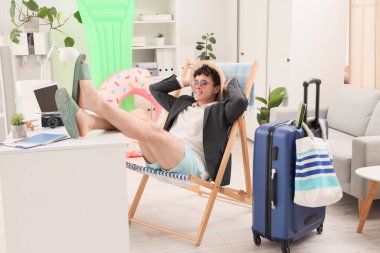 Genç işadamı yaz tatilini ofiste güverte koltuğunda bekliyor.