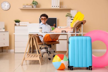 Kokteyl ve paletli genç iş adamı ofiste dizüstü bilgisayar kullanıyor. Yaz tatili