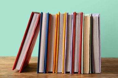 Turkuaz arka plana karşı ahşap masadaki renkli kitaplar.