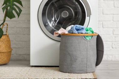 Çamaşır odasında çamaşır makinesinin yanında kirli çamaşırlarla dolu sepet.