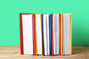 Ahşap masa üzerinde yeşil arka plana karşı renkli kitaplar dizisi