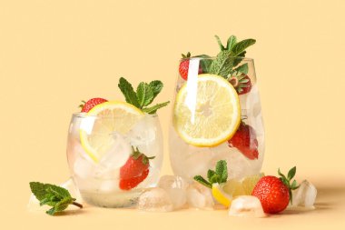 Turuncu arka planda taze çilek, limon ve nane yapraklı buz küpleri.