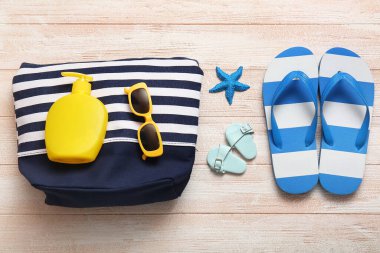 Beyaz ahşap arka planda güneş kremi ve plaj aksesuarları olan kompozisyon