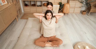 Young woman getting Thai massage from therapist in spa salon