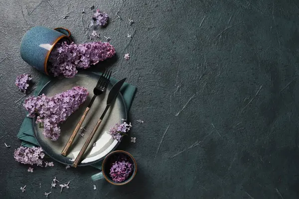 Koyu arkaplanda leylak çiçekleri olan güzel bir masa.