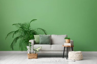 Oturma odasında kanepe, masa ve yeşil bitkiler var.