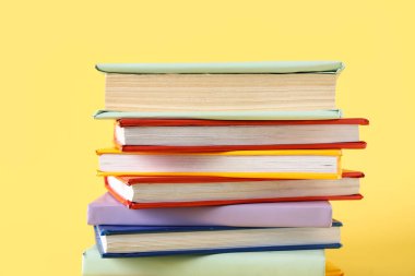Sarı arkaplan üzerine renkli kitap yığını