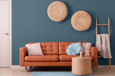 Oturma odasının içinde kahverengi kanepe, sepet ve rattan puflar var.