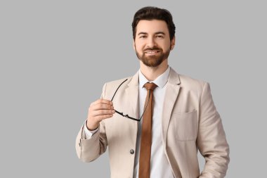 Açık arkaplanda gözlüklü, şık bej takım elbiseli yakışıklı bir iş adamı.