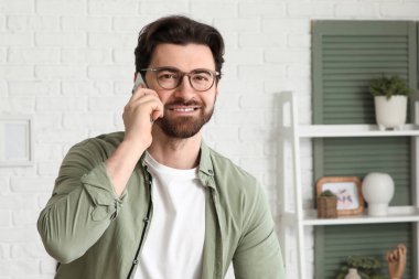 Evde cep telefonuyla konuşan yakışıklı adam.