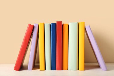 Beyaz ahşap masa üzerinde bej arka plana karşı renkli kitaplar dizisi