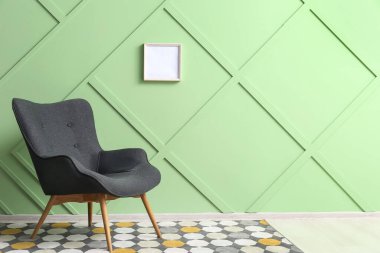 Modern grey armchair near green wall
