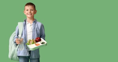 Beslenme çantası ve yeşil arka planda bir şişe suyu olan küçük bir okul çocuğu.