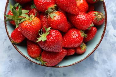 Mavi arka planda taze çilekli kase