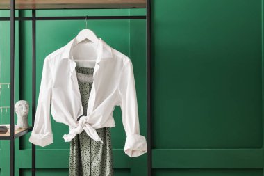 Yeşil duvarın yanında giysileri olan raf ünitesi