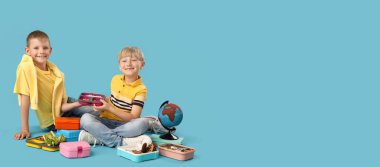 Beslenme çantaları ve küresi olan küçük çocuklar mavi arka planda oturuyorlar ve mesaj için yer var.