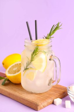 Ahşap pano ve eflatun arkaplanda taze limonata bulunan mason kavanozu.