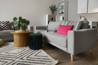 Gri kanepeleri ve kahve masasında çiçekleri olan şık bir oturma odası.