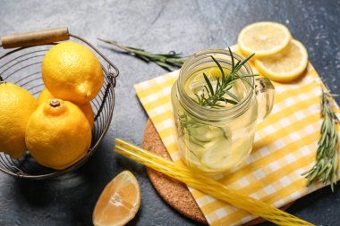 Mason kavanozu biberiyeli taze limonata ve mavi arka planda limonlar, yakın plan.