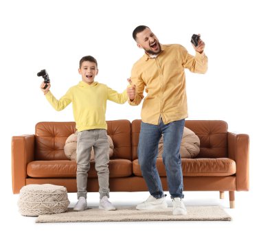 Mutlu baba ve oğlu beyaz arka planda kahverengi deri kanepenin yanında video oyunu oynuyorlar.