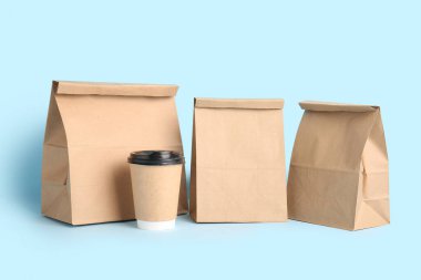 Mavi arka planda kahve fincanı olan kağıt poşetler. Yemek dağıtım servisi.