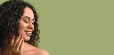 Yeşil arka planda sağlıklı bir cildi olan güzel, mutlu bir Afro-Amerikalı kadın.