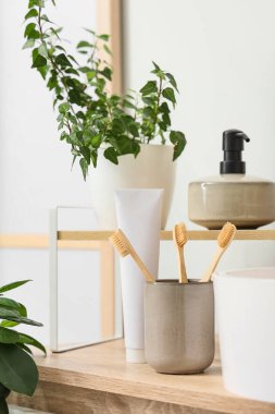 Diş macunu, sabun ve çiçek dolu fırça tutacağı banyodaki masada.