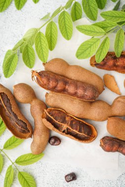 Beyaz arka planda lezzetli tamarindler, yapraklar ve tohumlar