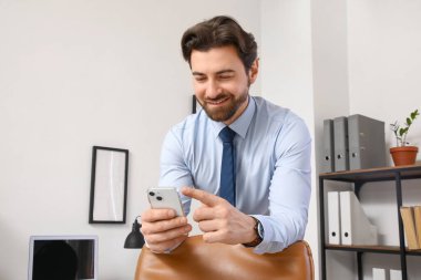 Ofiste cep telefonuyla çalışan yakışıklı iş adamı.